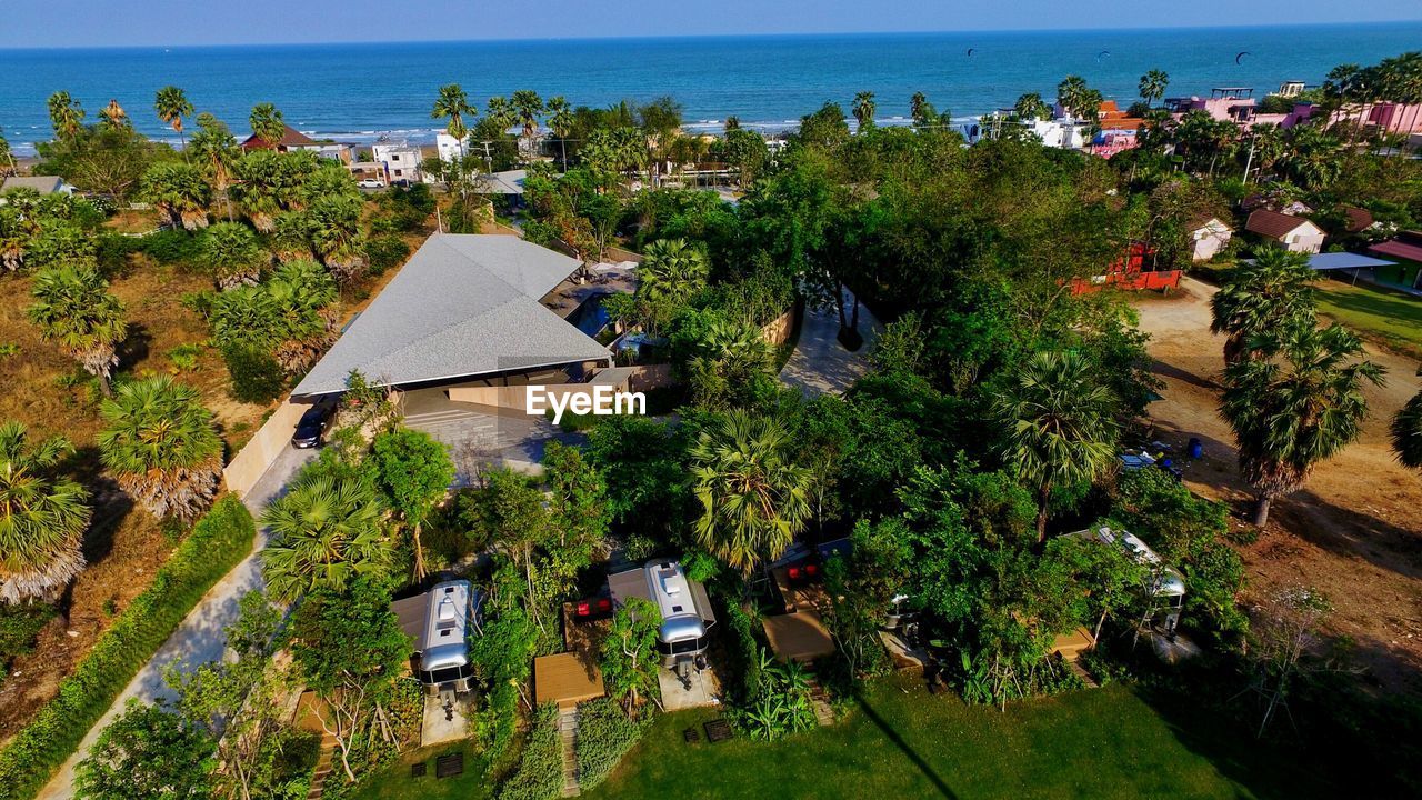 High angle view of houses by sea against trees