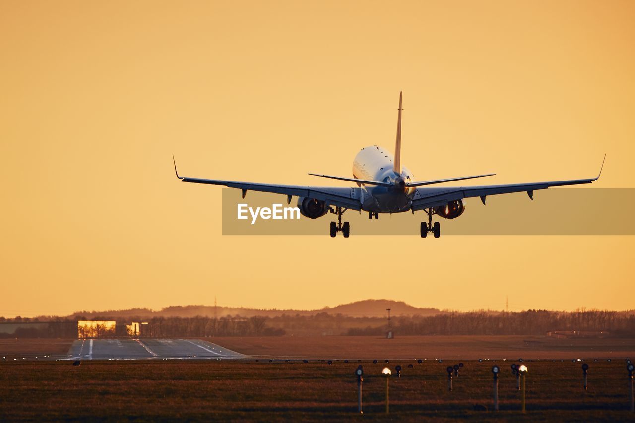 Airplane landing on runway. traffic at airport at golden sunset. 