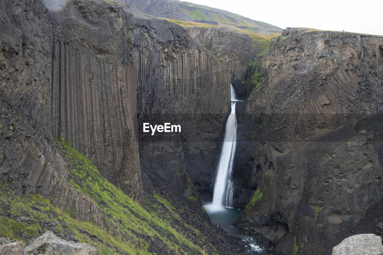 SCENIC VIEW OF WATERFALL IN MOUNTAINS