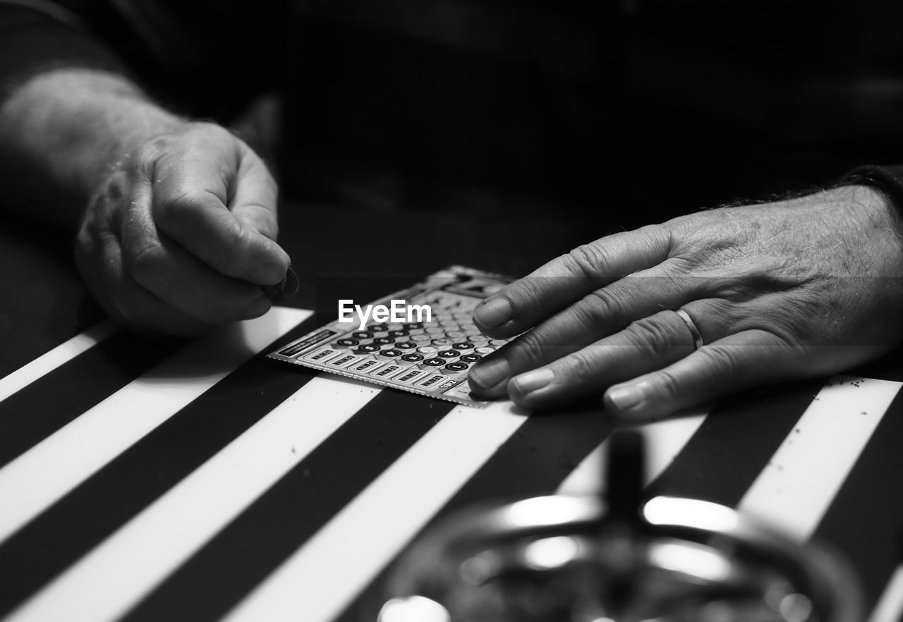 Close-up of man scratching lottery ticket