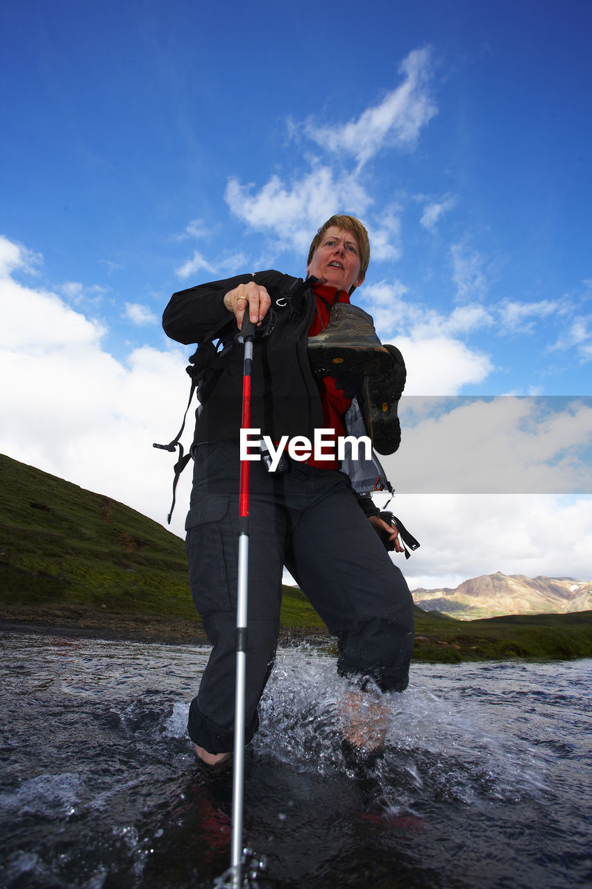 Mature woman crossing river on the laugavegur hiking trail