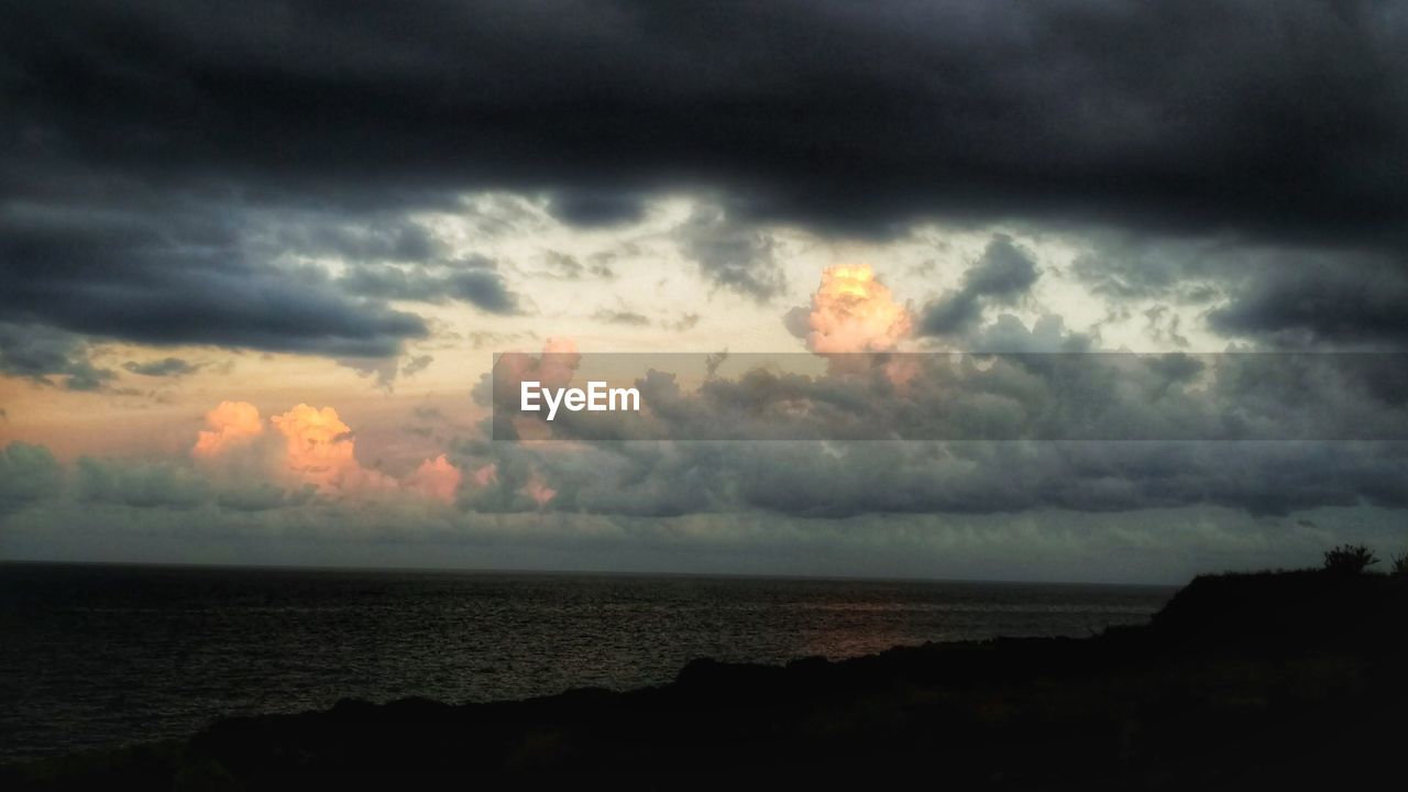 Scenic view of sea against cloudy sky at dusk