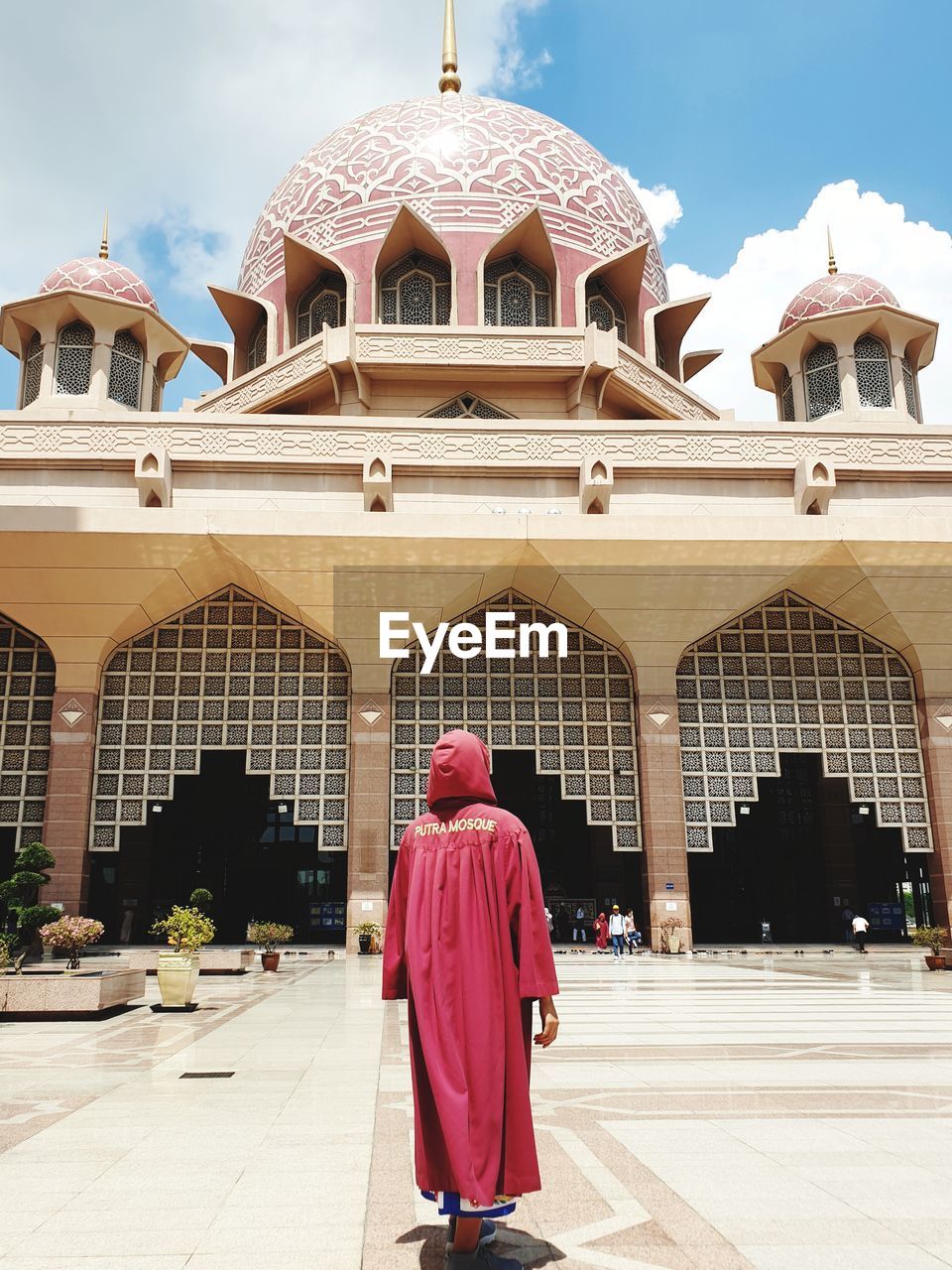 REAR VIEW OF MAN WALKING IN TEMPLE AGAINST BUILDINGS