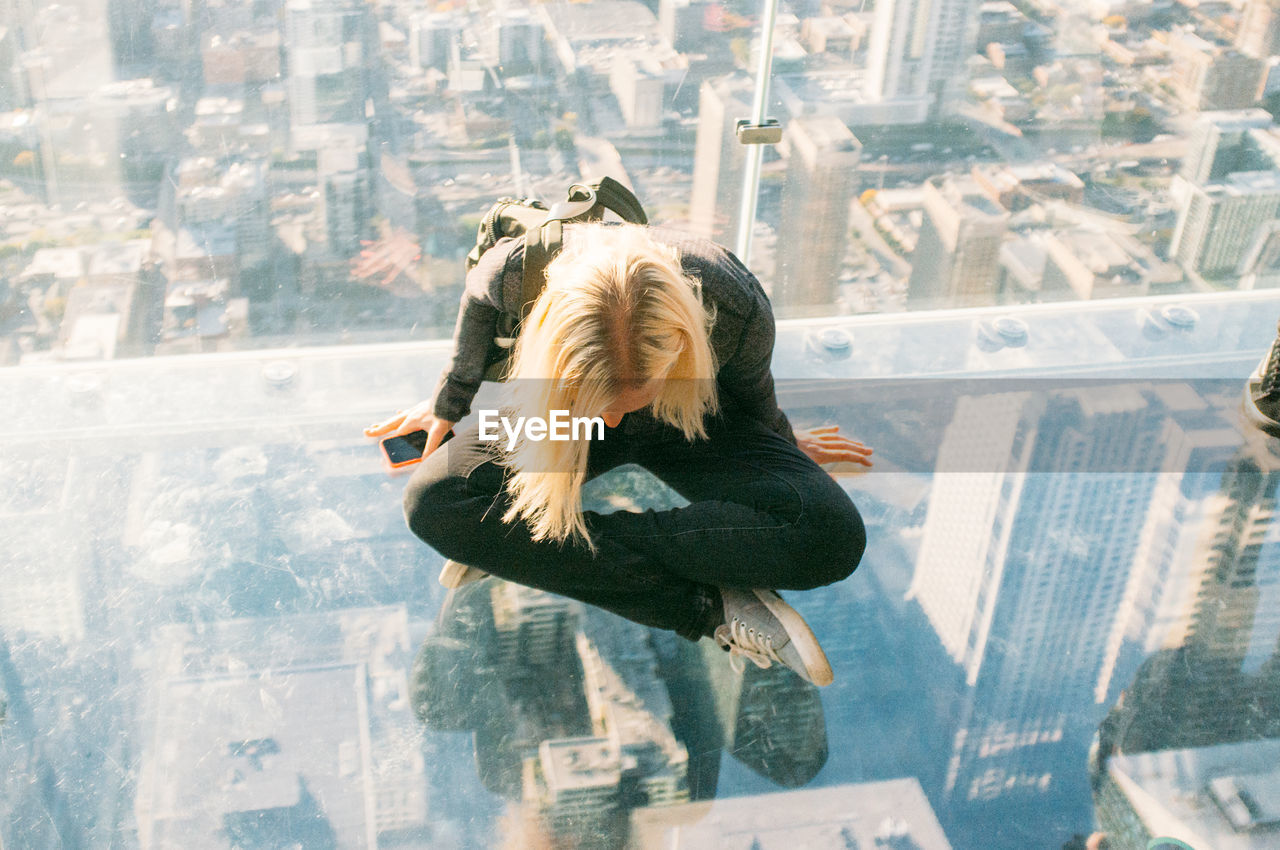 High angle view of woman sitting on glass at skydeck chicago in willis tower
