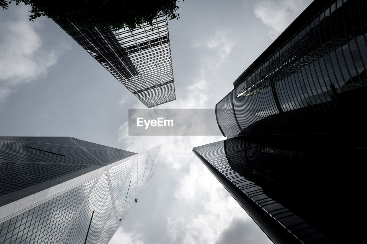 Low angle view of skyscrapers against cloudy sky