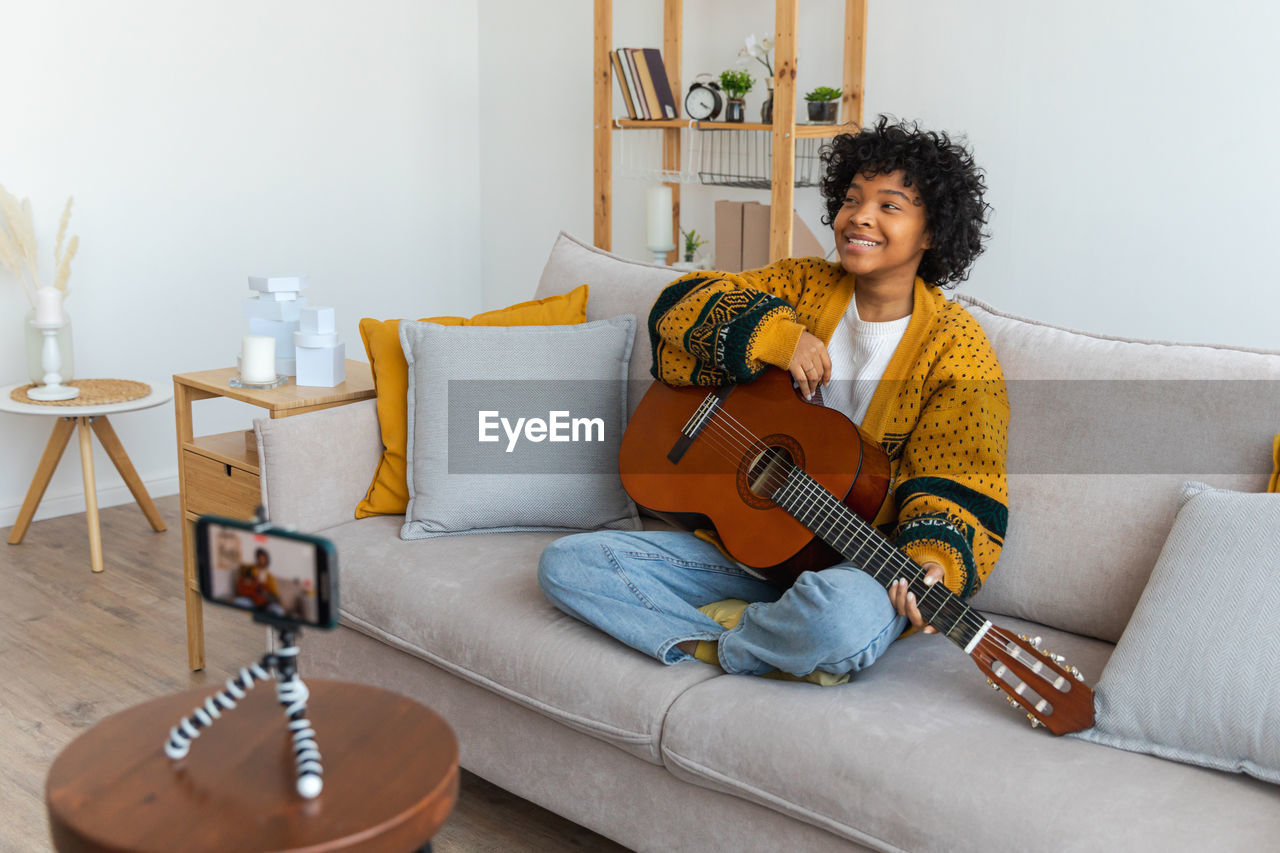 portrait of young woman using digital tablet while sitting on sofa at home