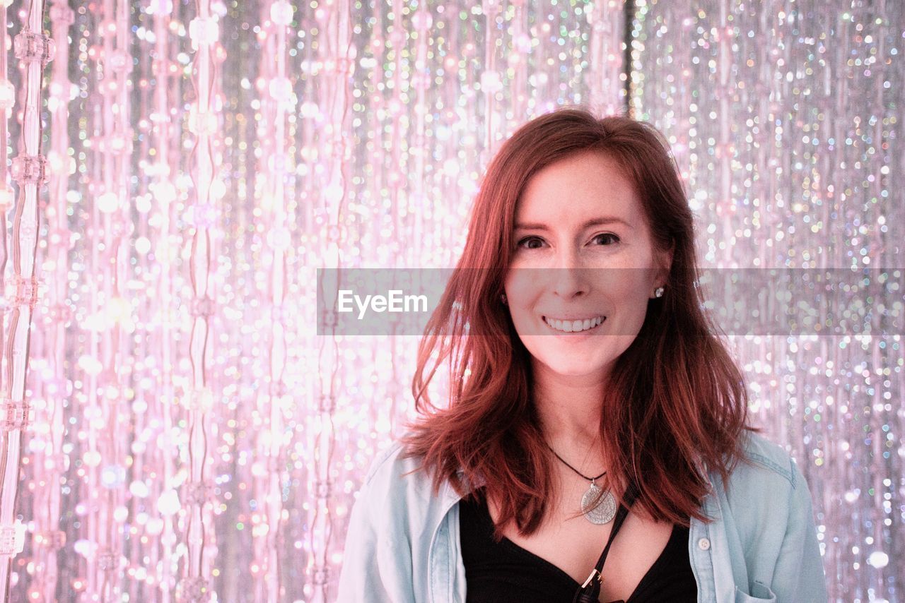 Portrait of smiling woman against illuminated lights