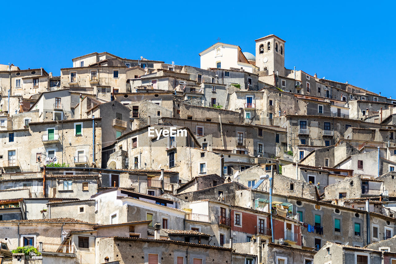 Buildings in city against clear blue sky