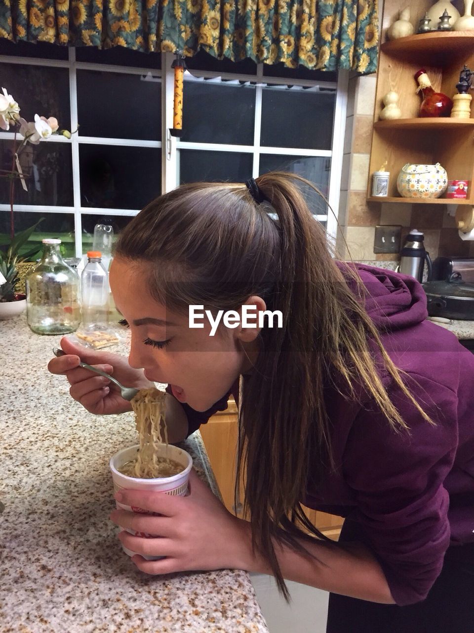 CLOSE-UP OF YOUNG WOMAN EATING FOOD IN BACKGROUND