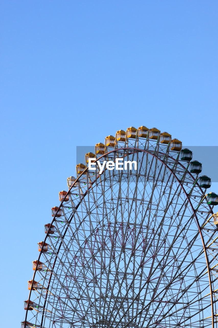 High section of cropped ferris wheel against clear blue sky