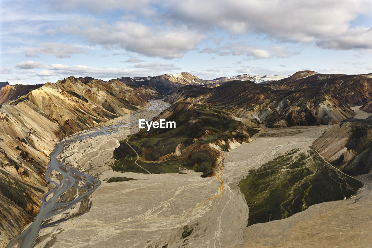 Arid riverbed in highlands against cloudy sky