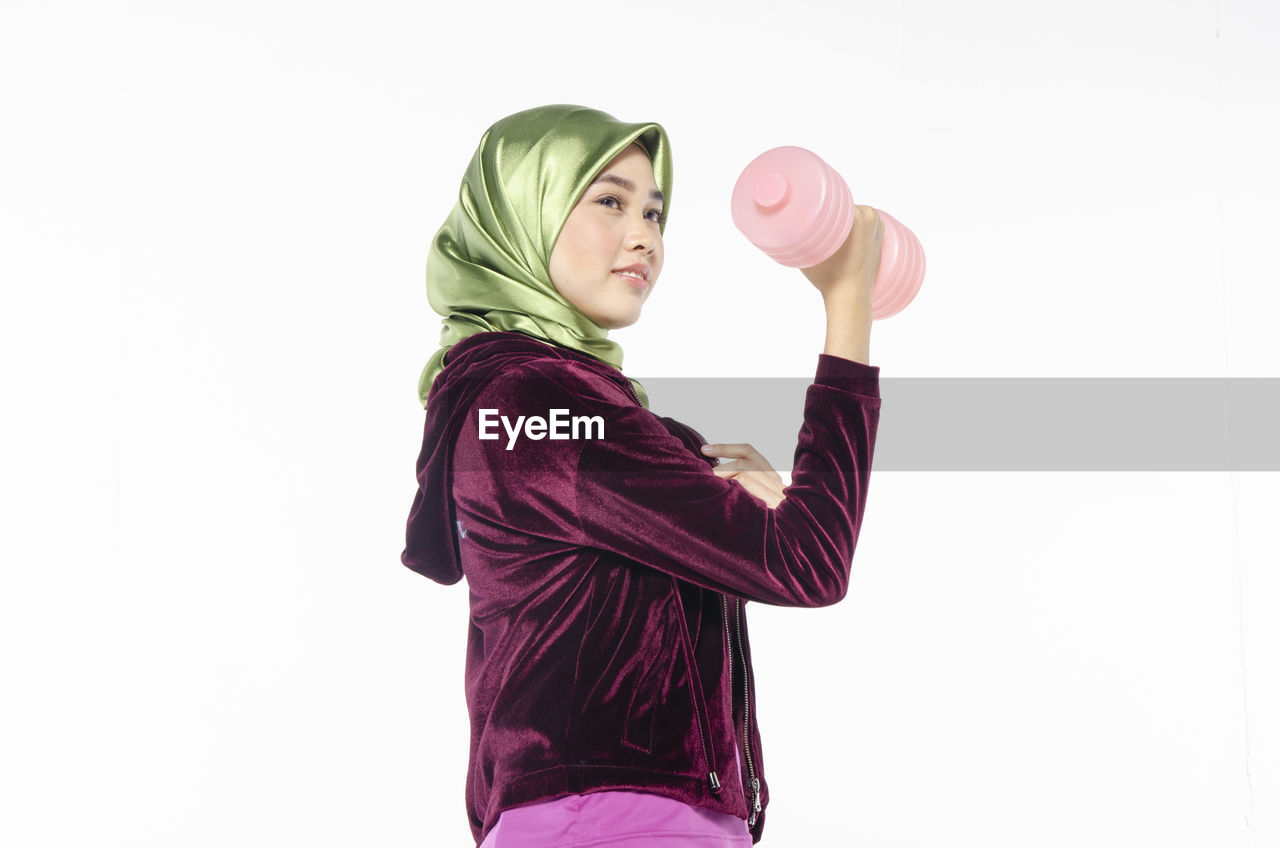 SIDE VIEW OF YOUNG WOMAN STANDING AGAINST PINK BACKGROUND