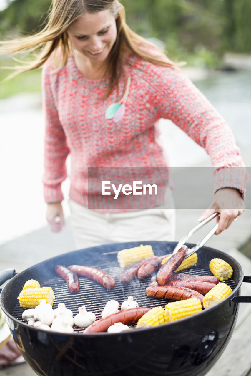Mid adult woman barbecuing outdoors