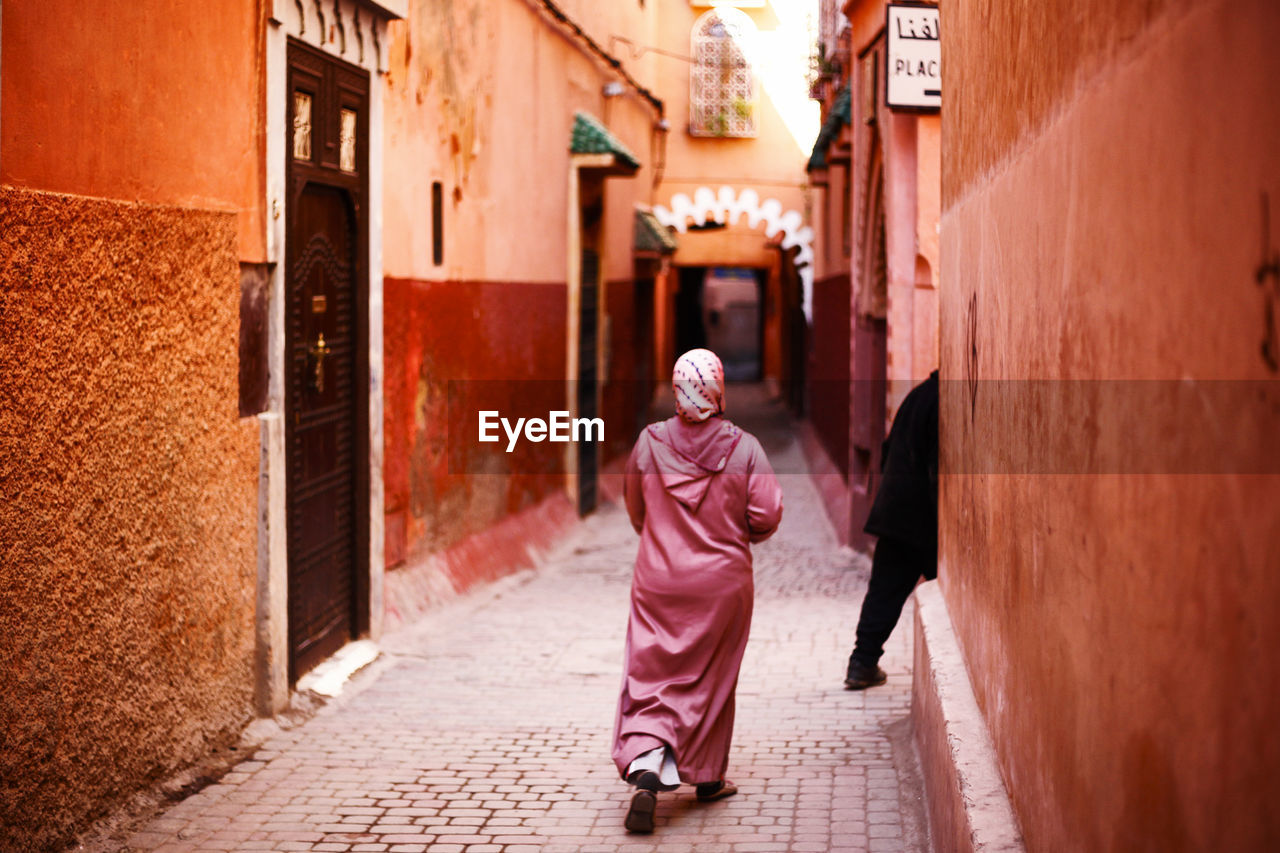 Rear view of woman walking on street amidst buildings