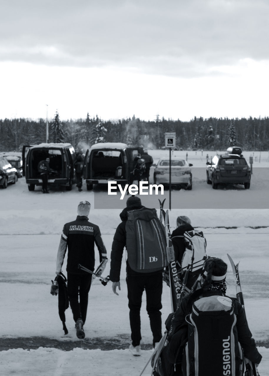 REAR VIEW OF PEOPLE WALKING ON ROAD AGAINST SKY