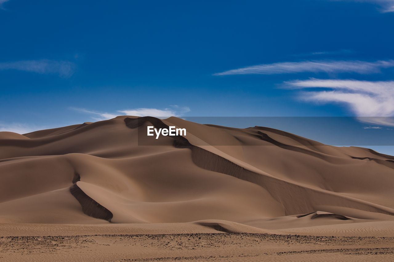 Sand dunes in desert against sky