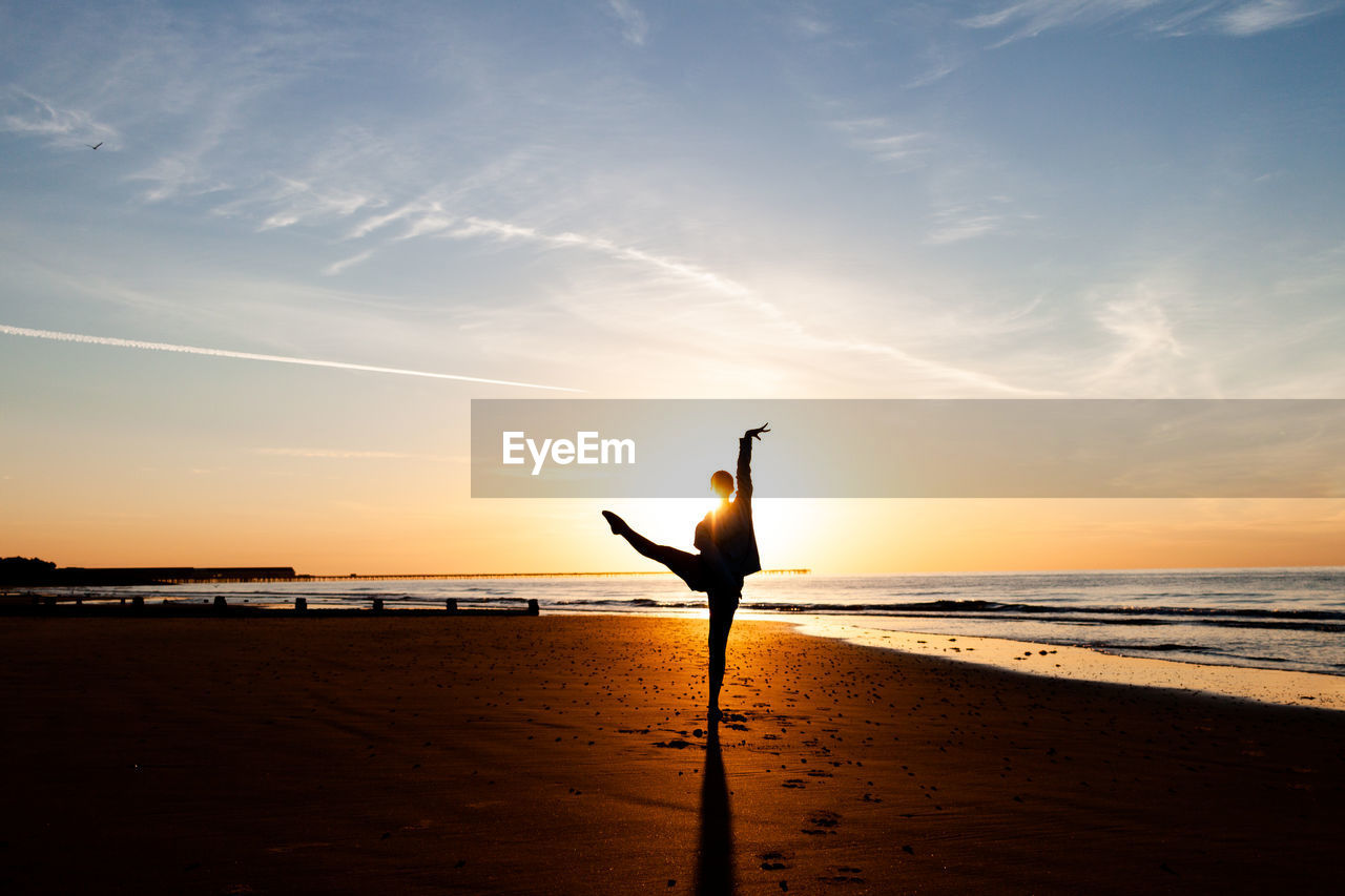 Silhouette of person on beach against sky during sunrise