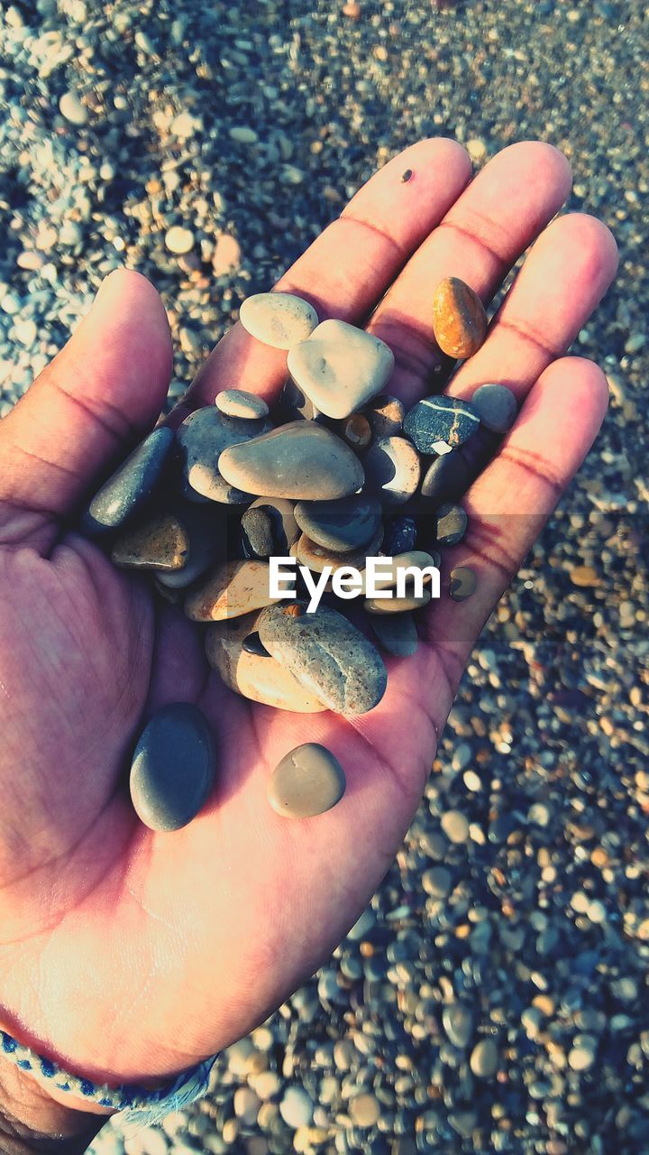 Close-up of man holding beach stones