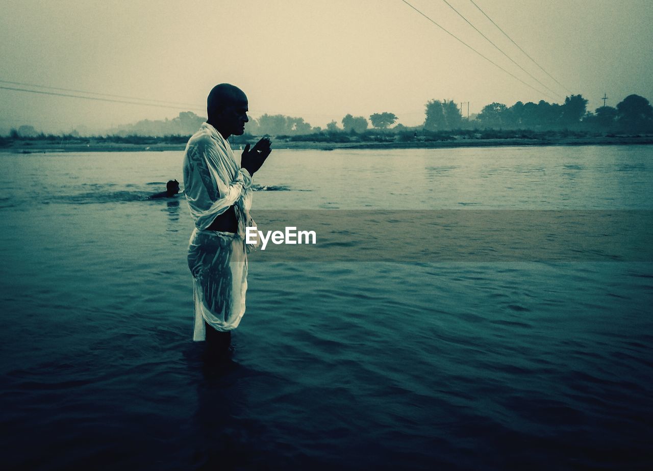 MAN IN LAKE AGAINST SKY