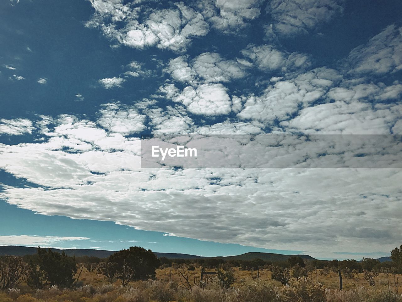 SCENIC SHOT OF COUNTRYSIDE LANDSCAPE AGAINST CLOUDY SKY