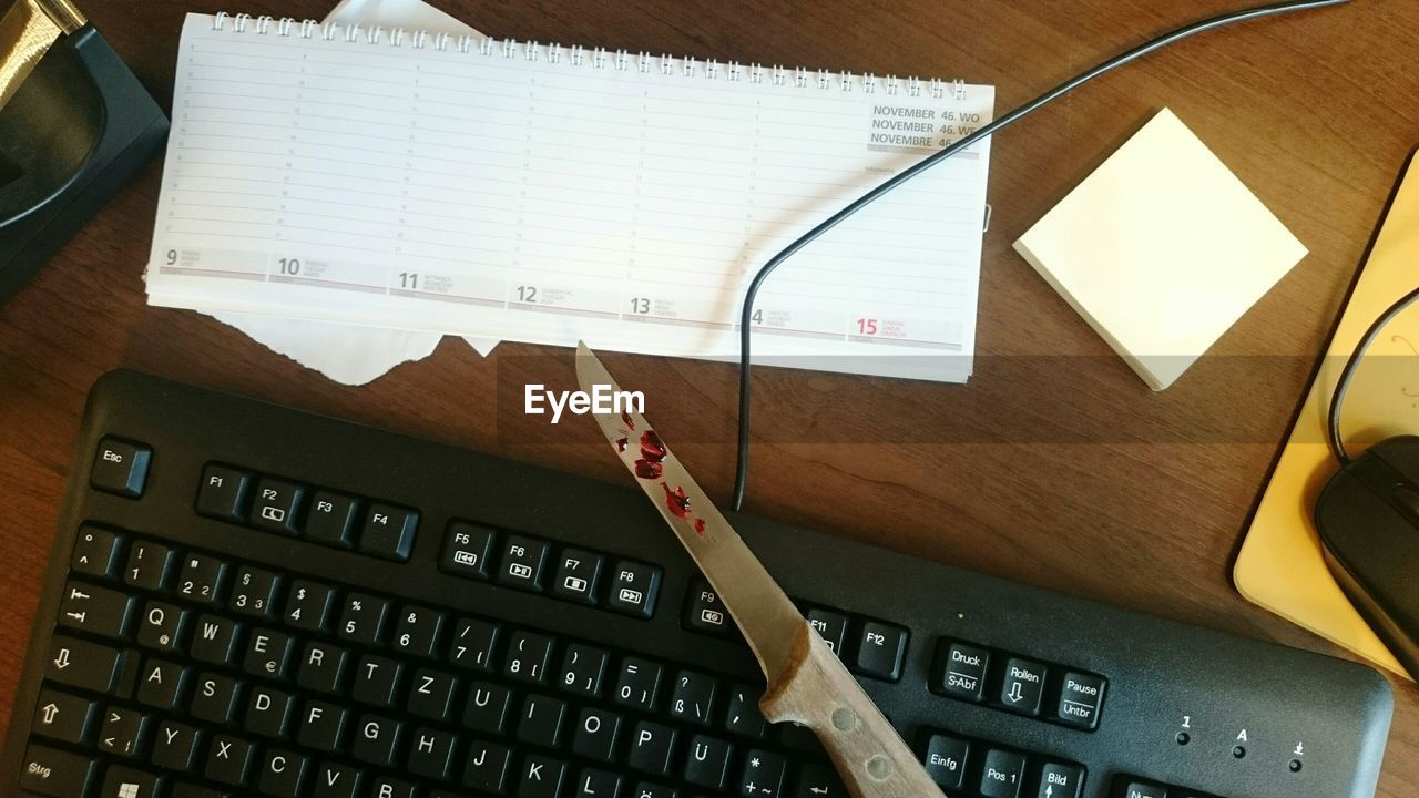 High angle view of knife on computer keyboard at table