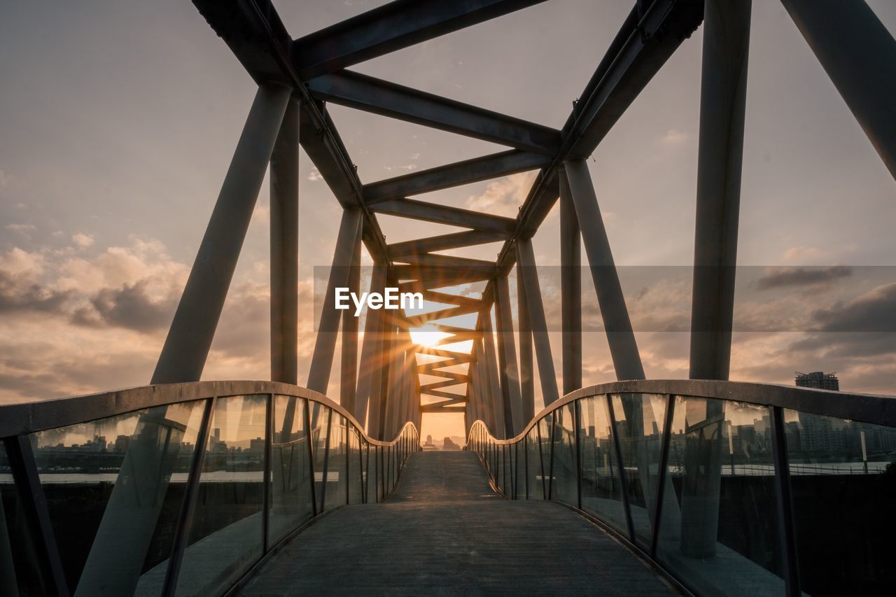 Bridge in city against sky during sunset