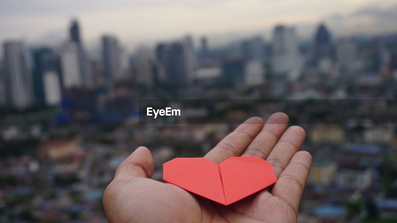 Close-up of hand holding heart shape against sky