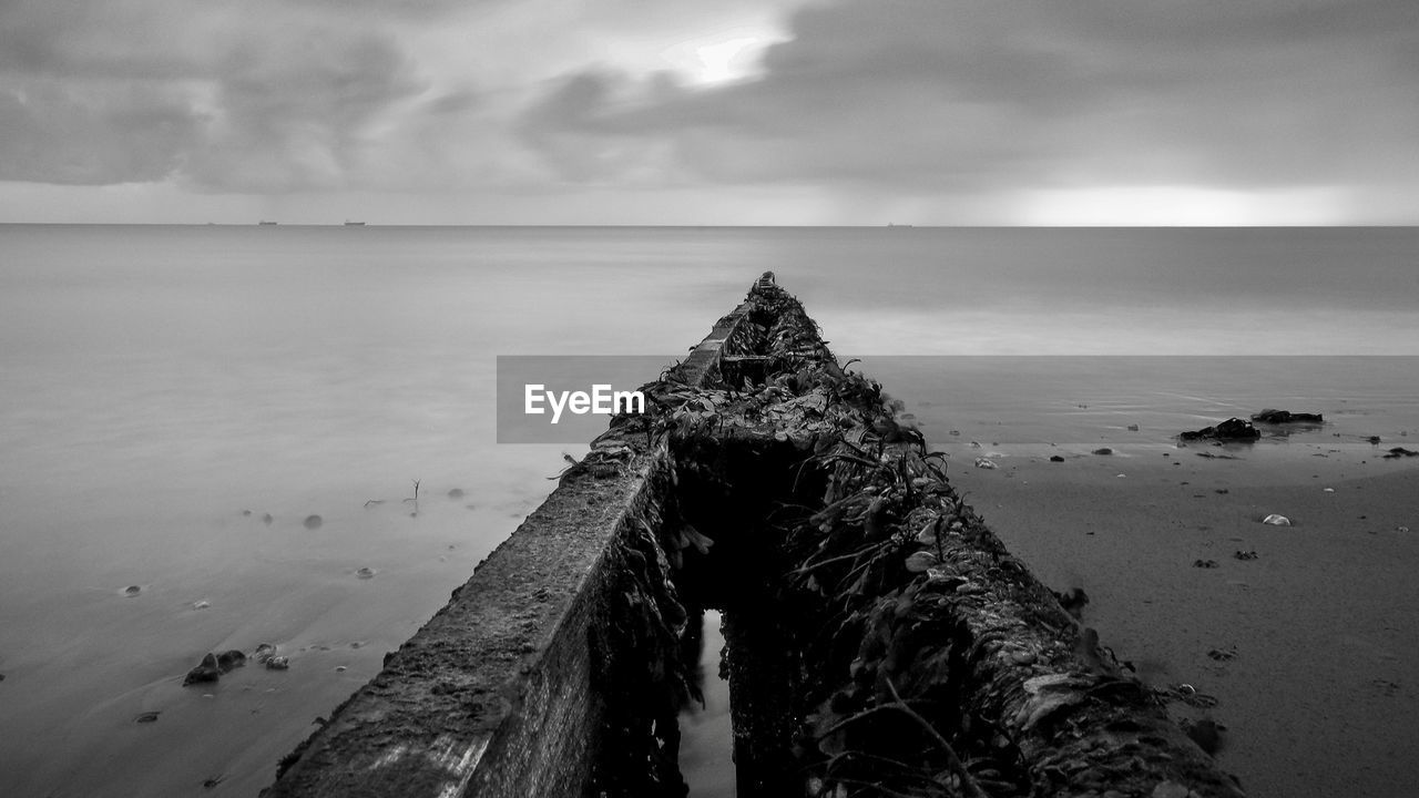 WOODEN POSTS ON PIER OVER SEA