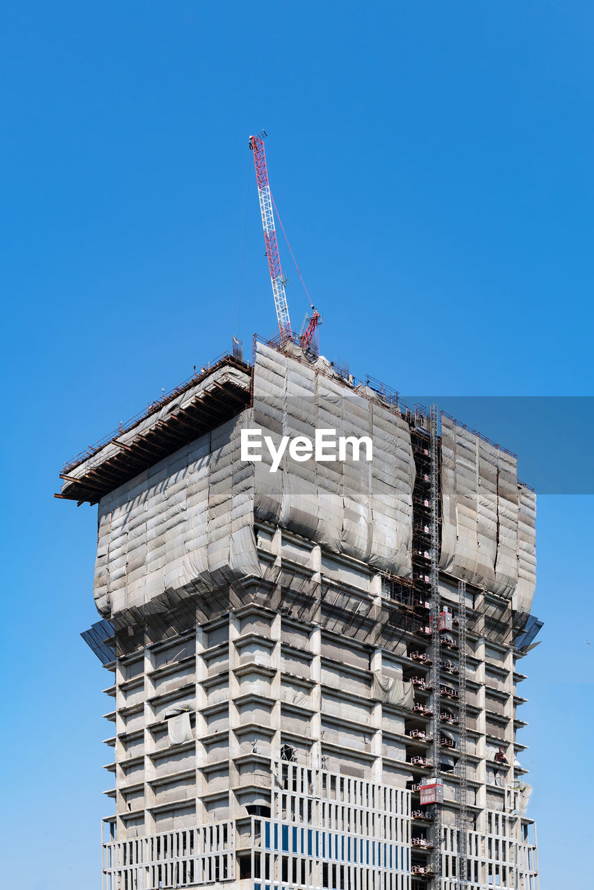LOW ANGLE VIEW OF CRANE AGAINST BUILDING