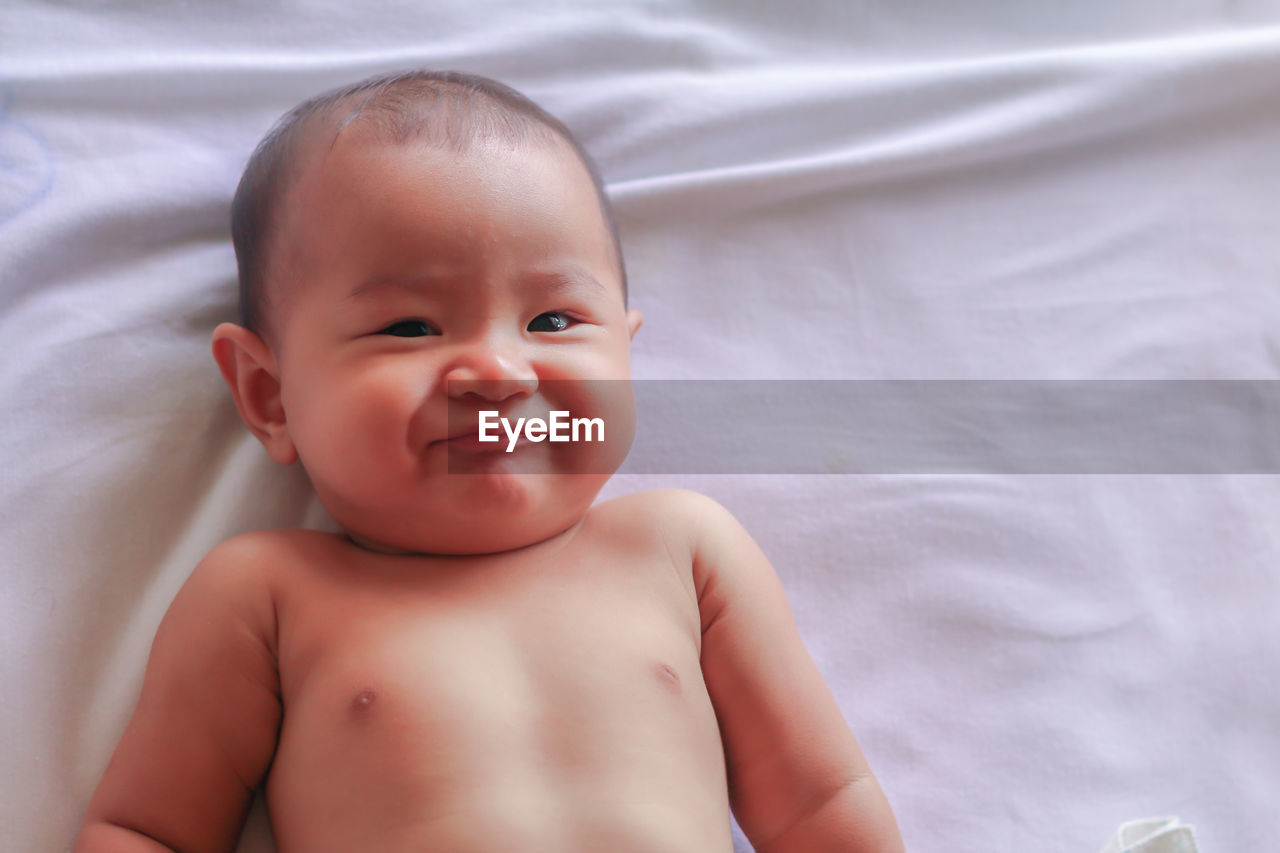 PORTRAIT OF BABY BOY LYING ON BED