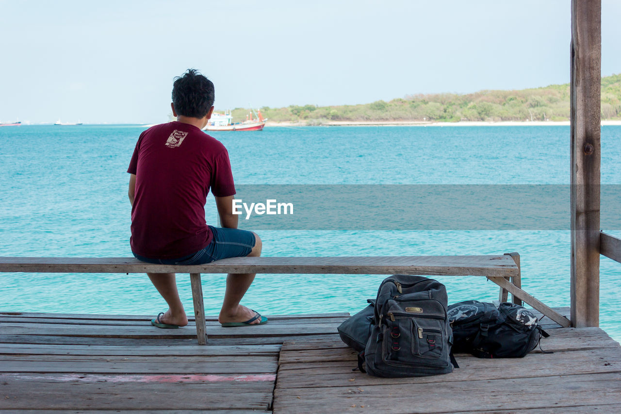 REAR VIEW OF WOMAN SITTING ON PIER