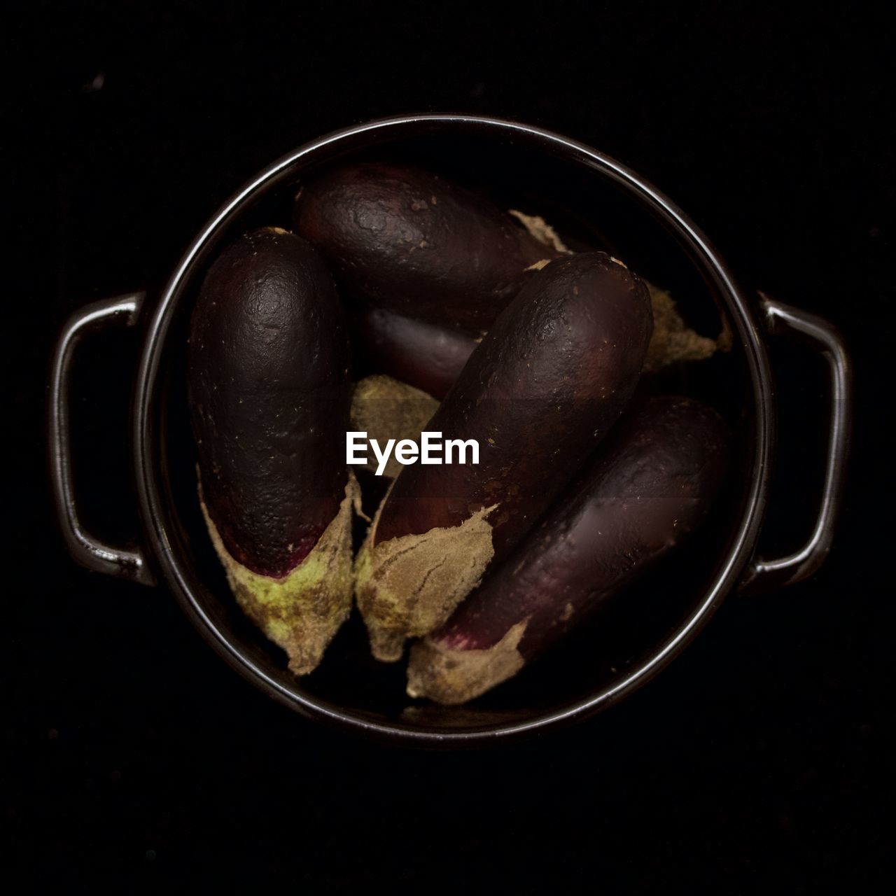 Close-up view of eggplants in bowl on black background