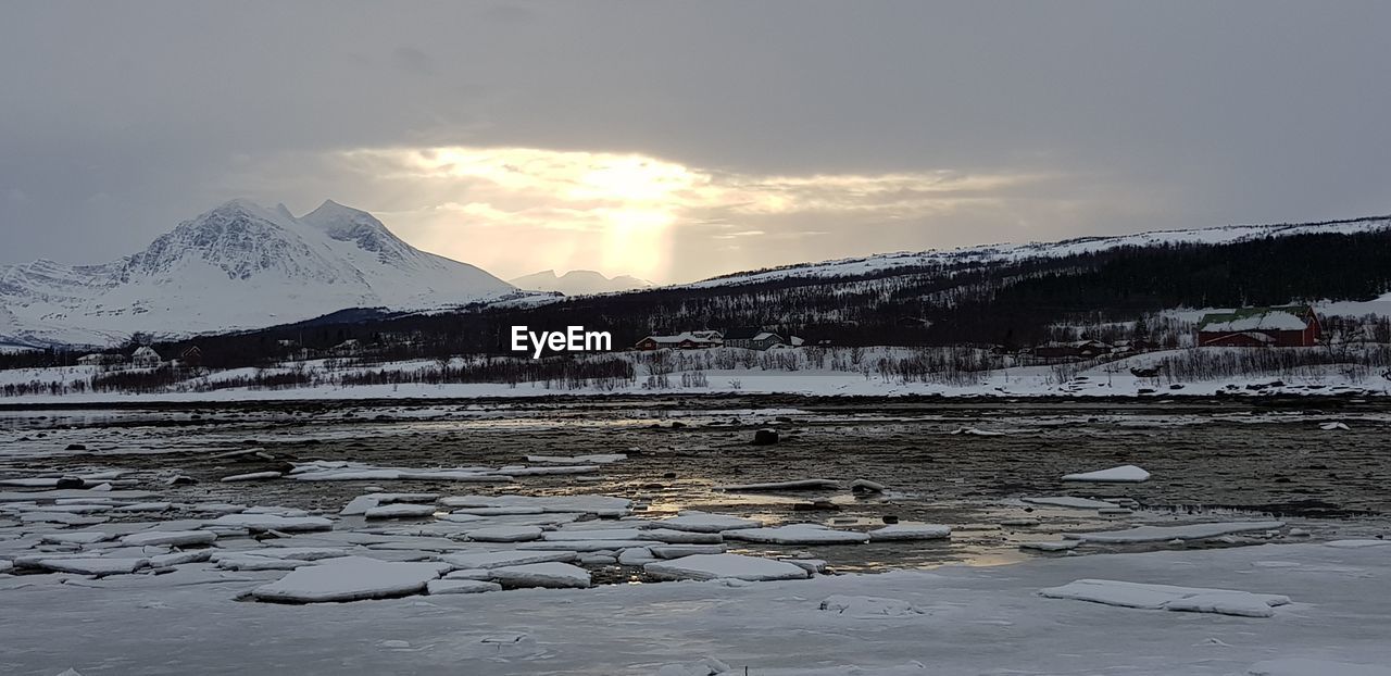 FROZEN RIVER BY SNOWCAPPED MOUNTAIN AGAINST SKY