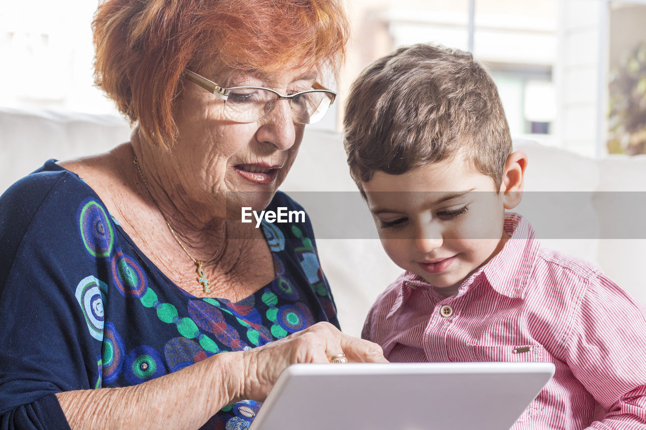 Grandmother showing digital tablet to boy at home