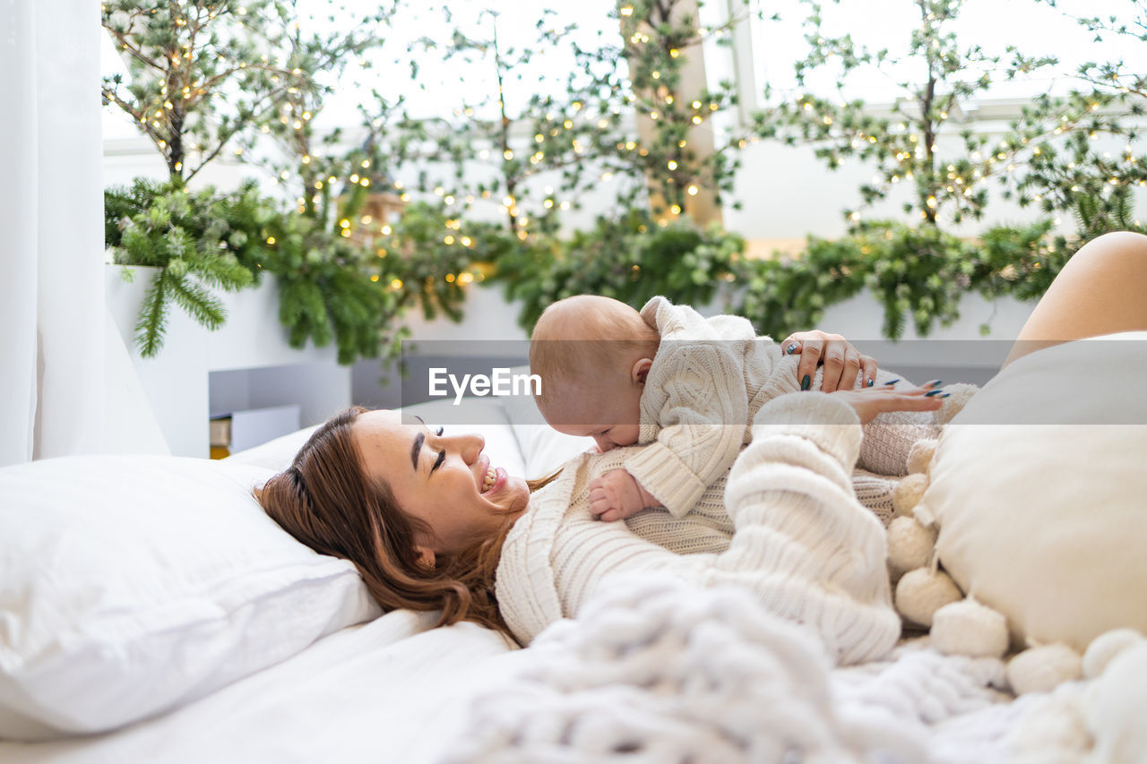 Young mother with child lying on bed at home