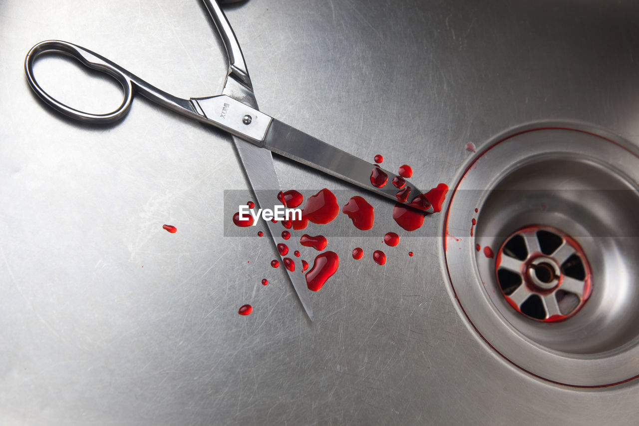 High angle view of scissor with blood drops at sink