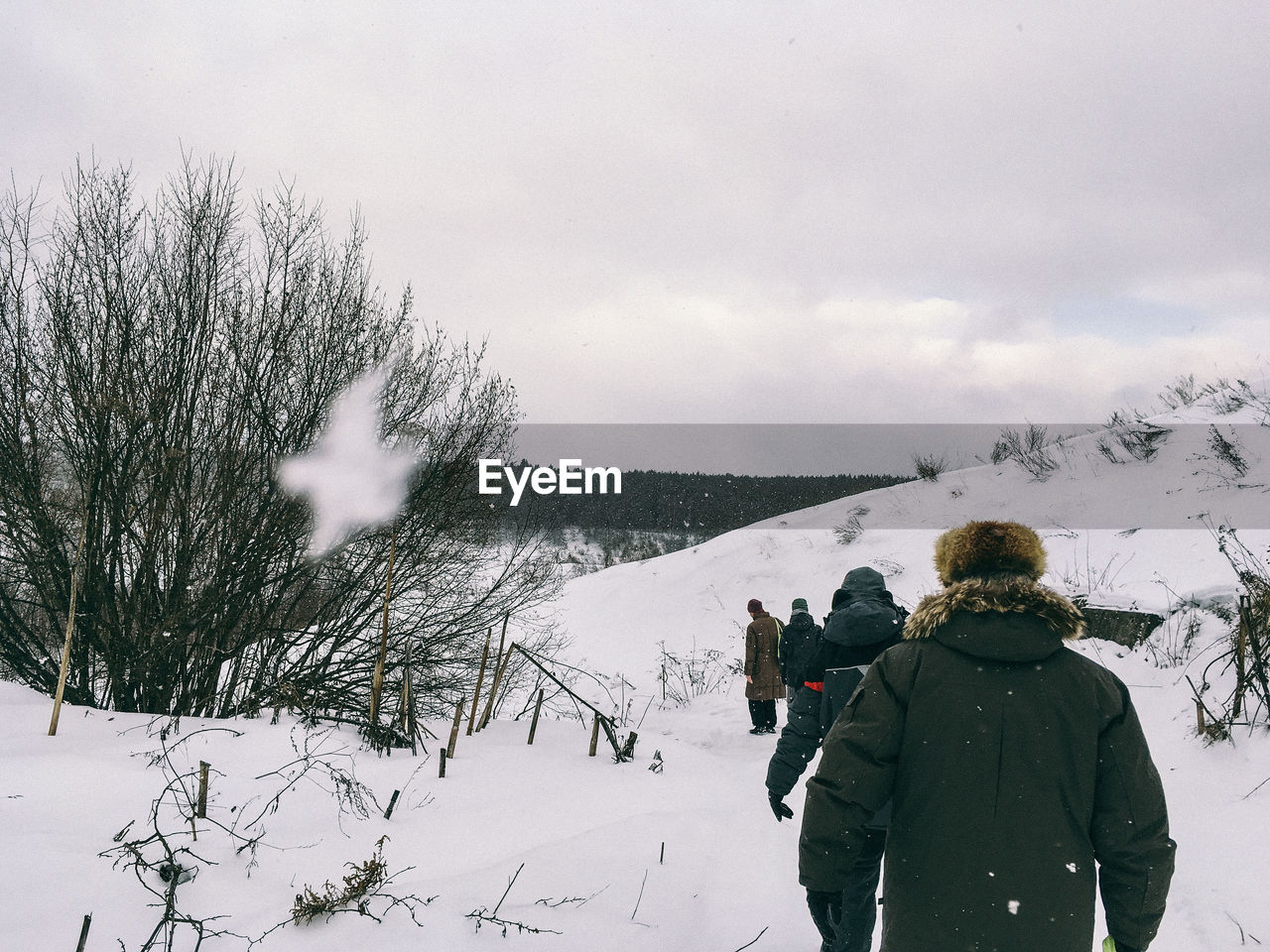 Rear view of people walking on snowy field during winter