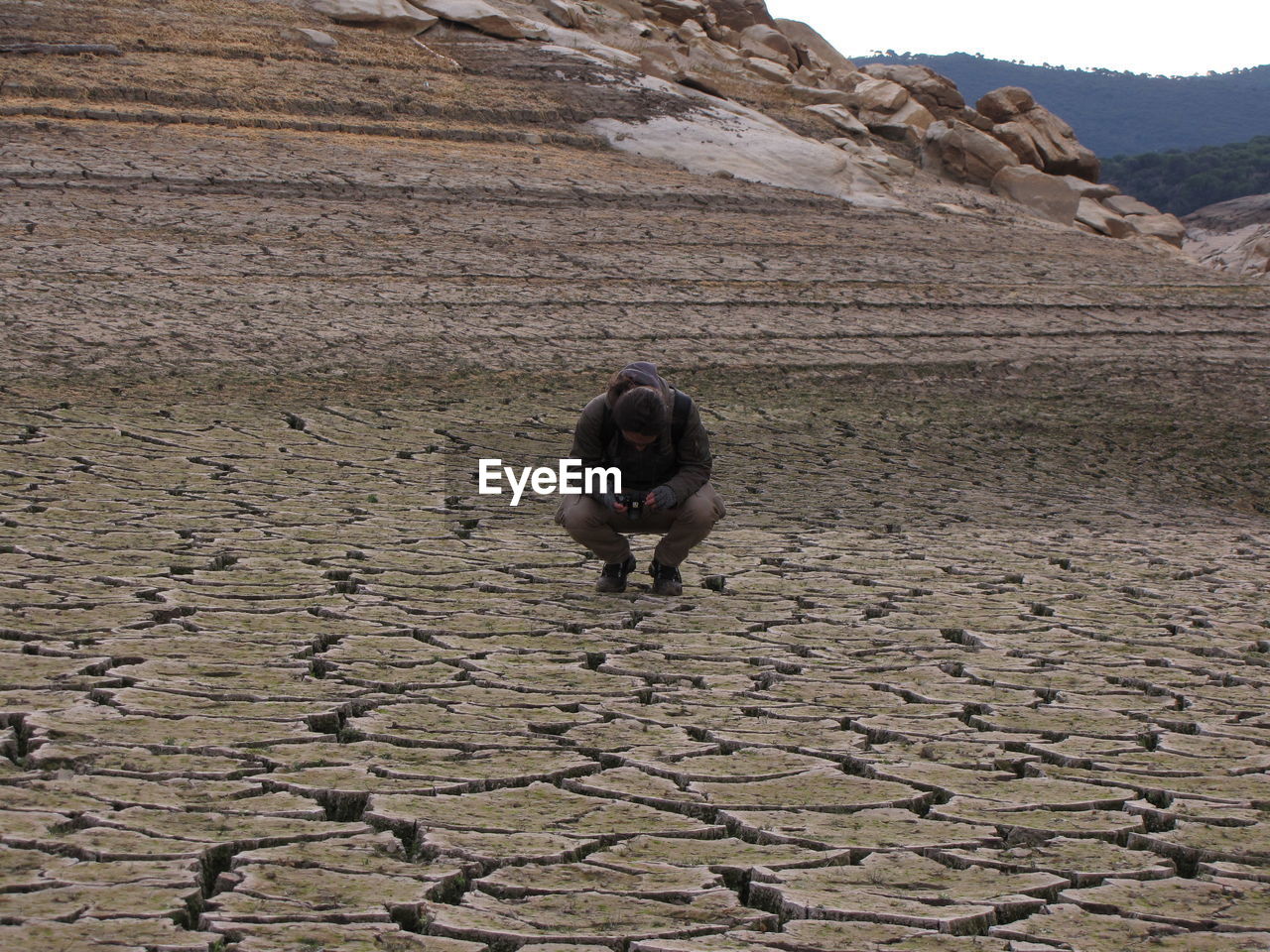 Man photographing on land against mountains