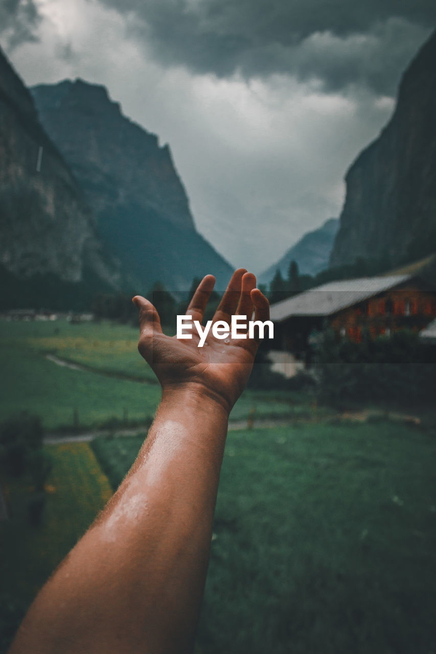 Close-up of human hand against mountain range