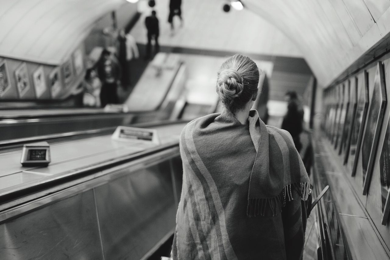 Rear view of woman wrapped in shawl standing on escalator at london underground