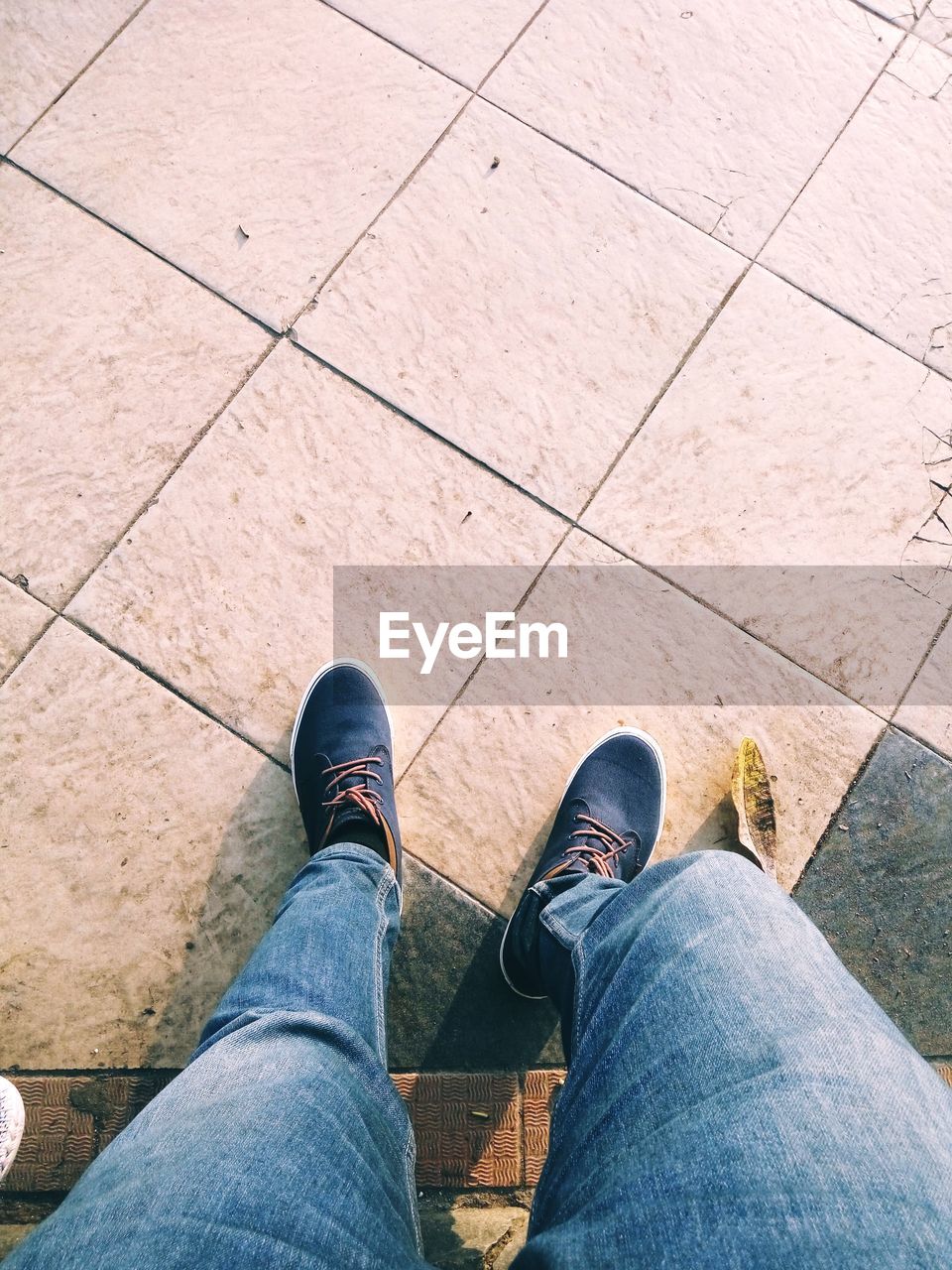 LOW SECTION VIEW OF MAN STANDING ON TILED FLOOR