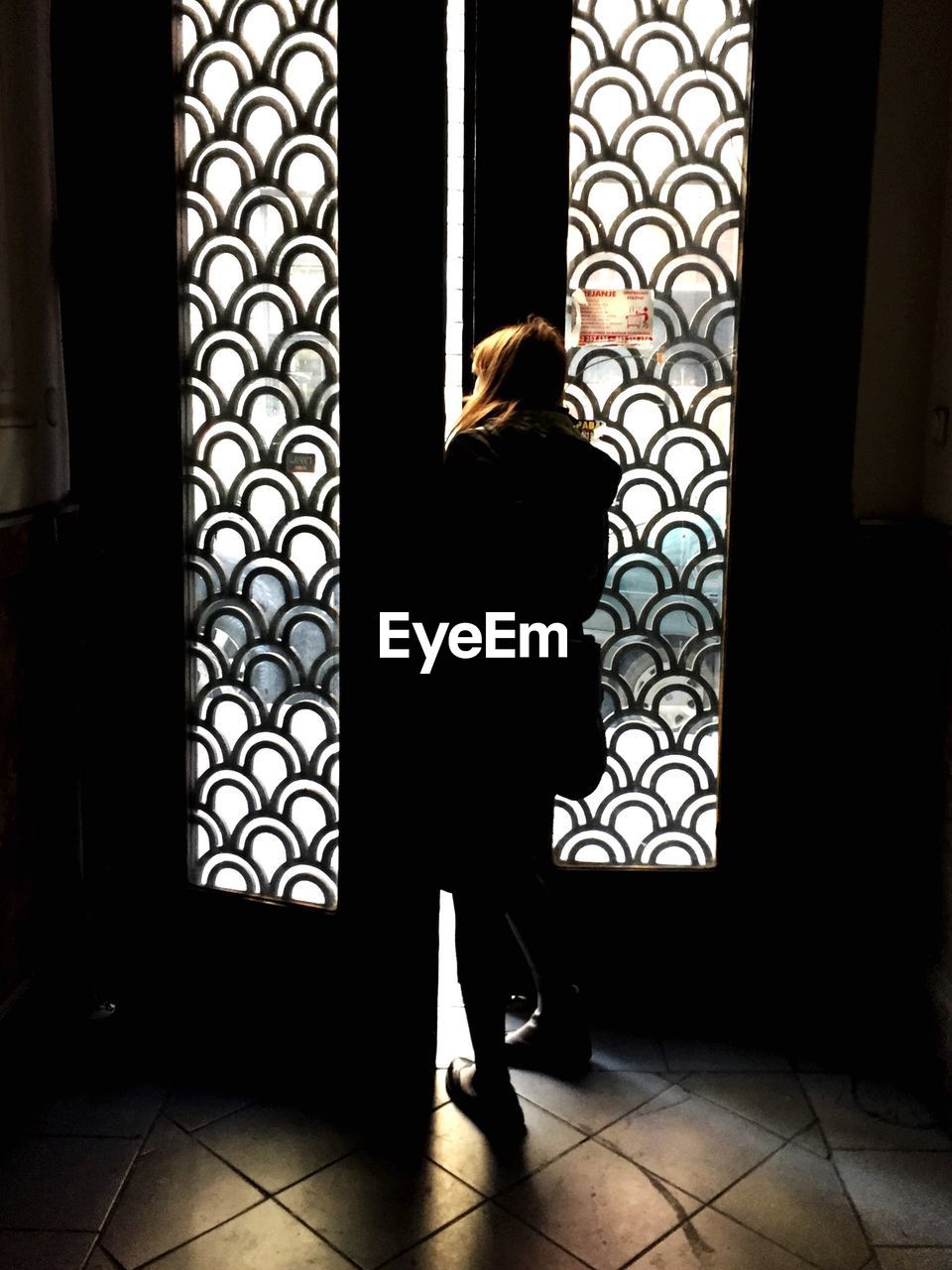 Rear view of woman looking through ajar door