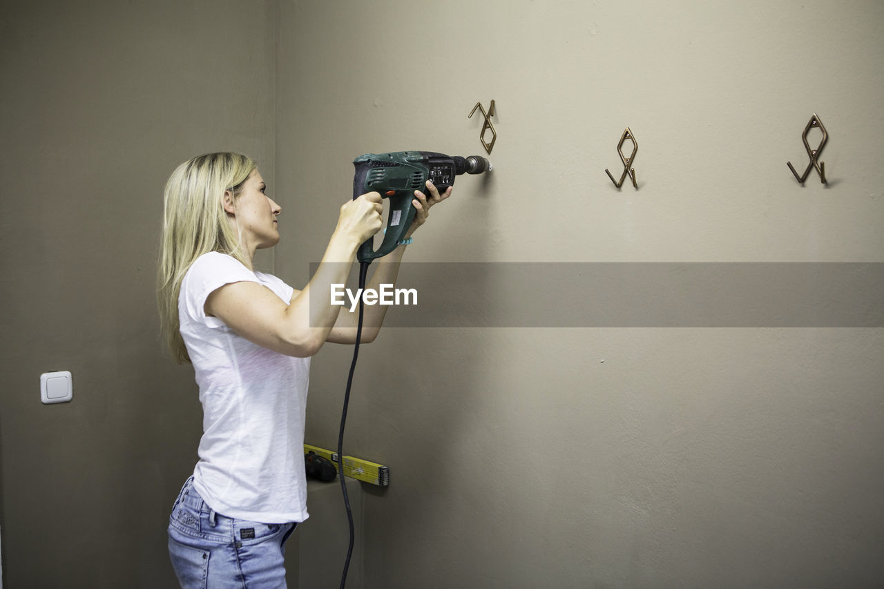 Woman drilling wall