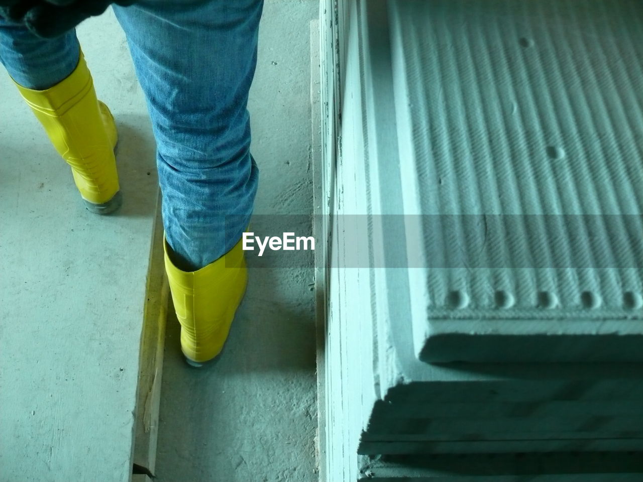 LOW SECTION OF MAN WEARING YELLOW SHOES ON BLUE SURFACE