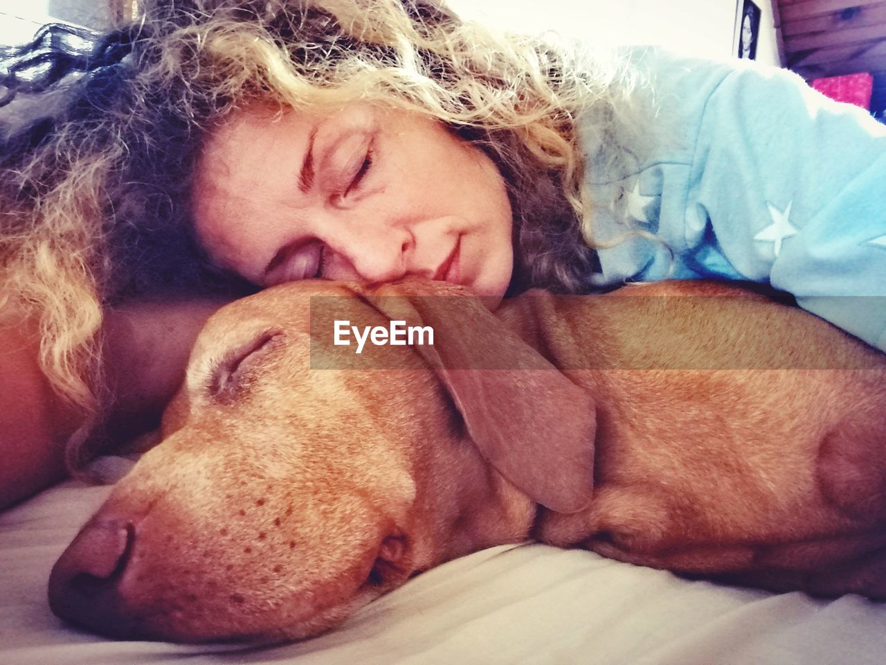 Mid adult woman with dog sleeping on bed at home