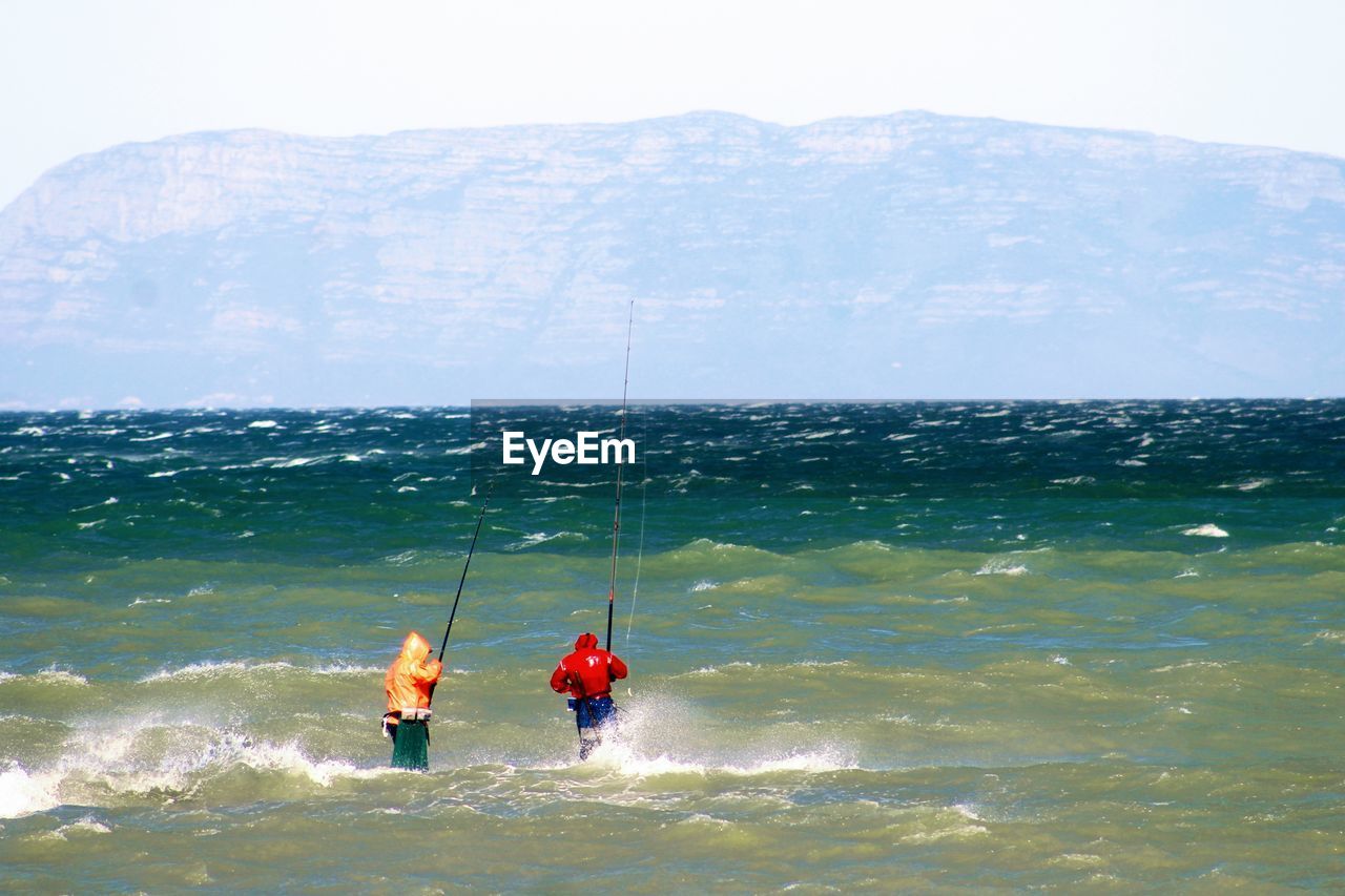 People fishing in sea against sky