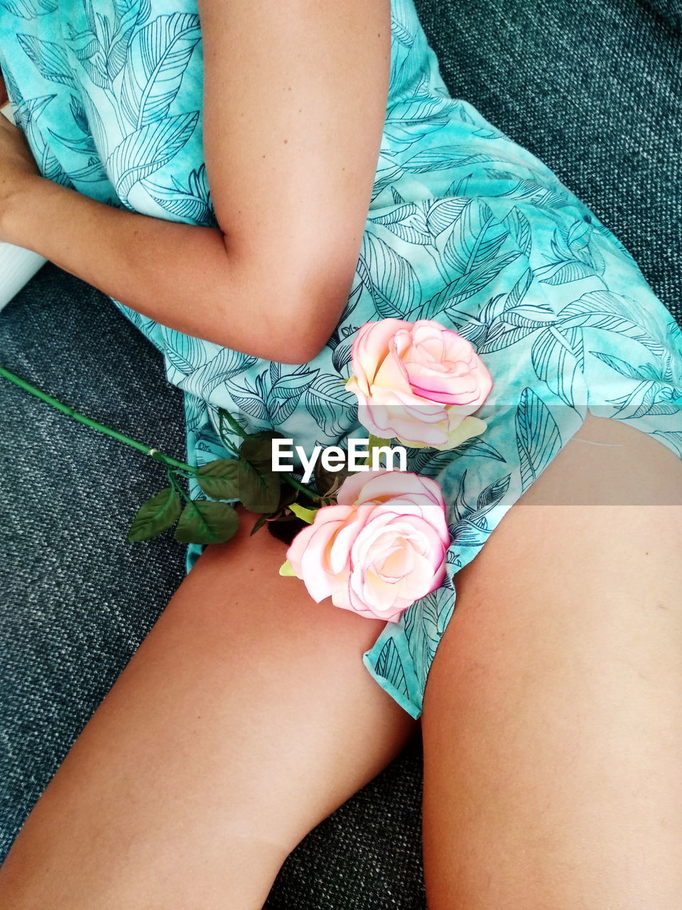 LOW SECTION OF WOMAN SITTING ON BED BY POTTED PLANT