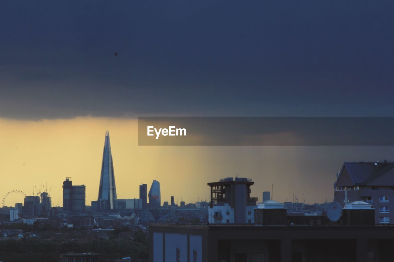 Modern buildings against sky during sunset