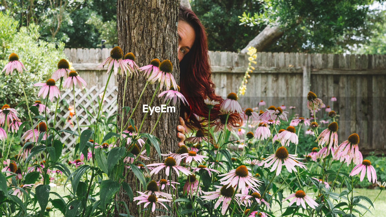 Woman hiding behind tree at park