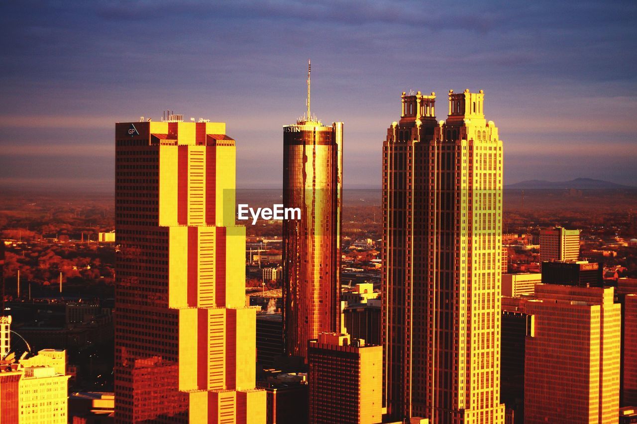 Illuminated cityscape against sky during sunset